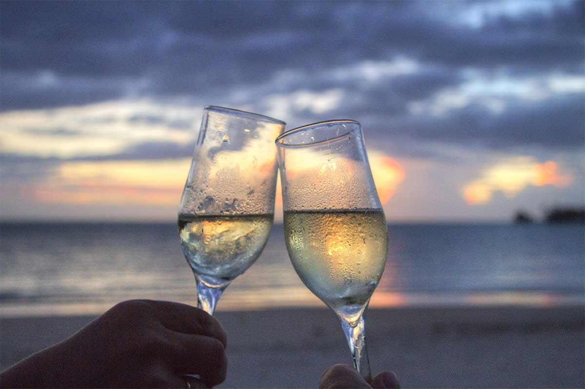bore coupes de champagne sur la plage au coucher du soleil