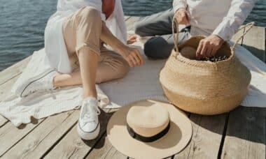 femme en baskets blanches assise sur un quai en bois a cote de chapeau marron
